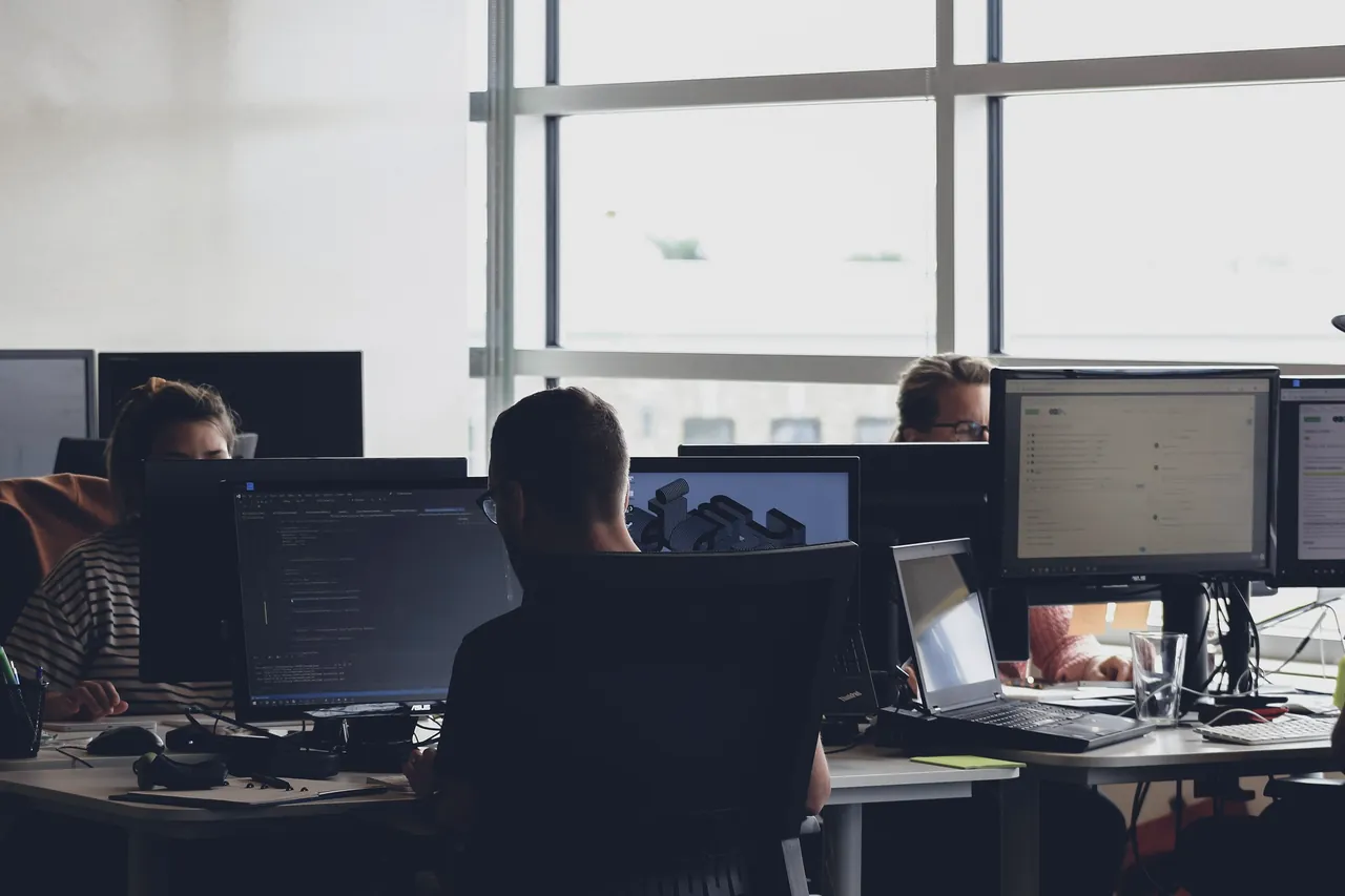 People working at rows of monitors in an open office