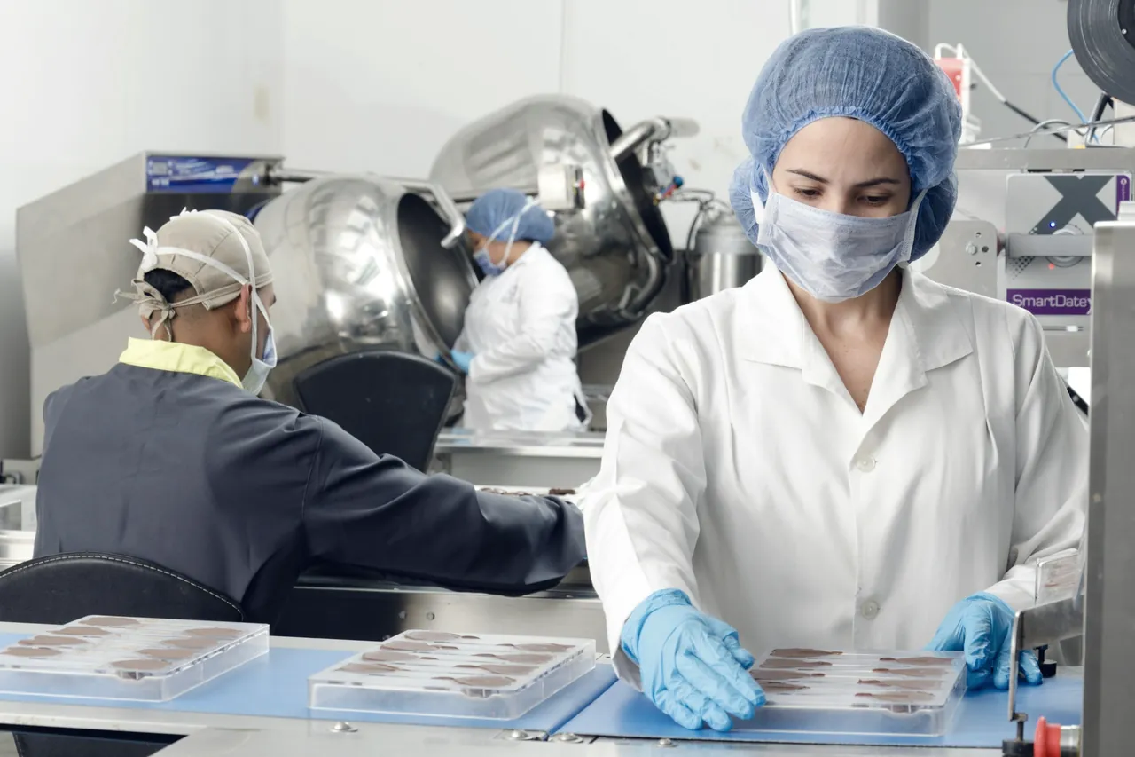 Food workers in hairnets, masks and gloves packing trays