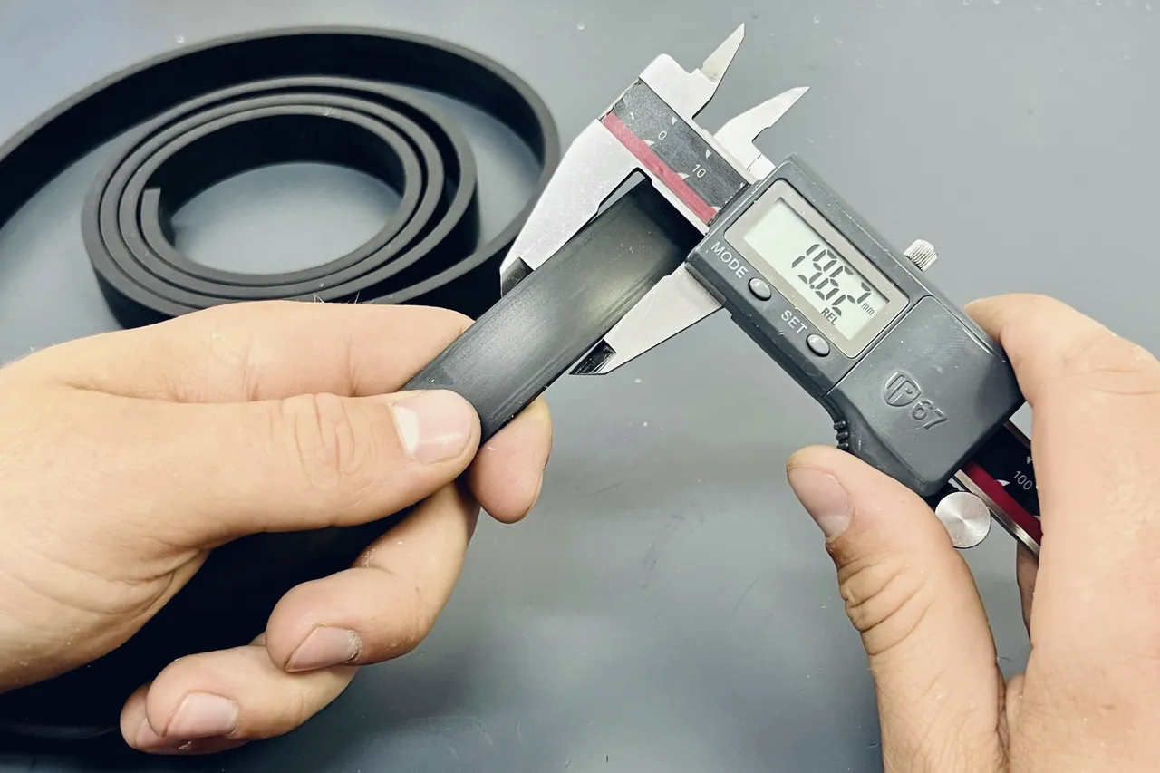 Hands measuring a rubber part with a digital caliper
