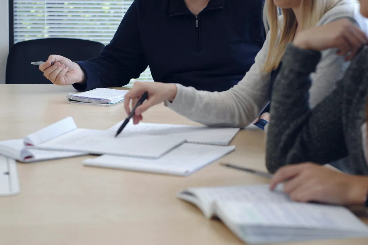 People working through papers and notebooks around a table